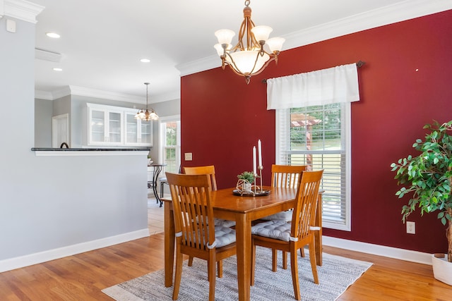 dining area with crown molding, a chandelier, and light hardwood / wood-style flooring