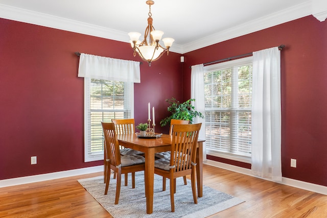 dining area featuring an inviting chandelier, light hardwood / wood-style floors, a healthy amount of sunlight, and crown molding