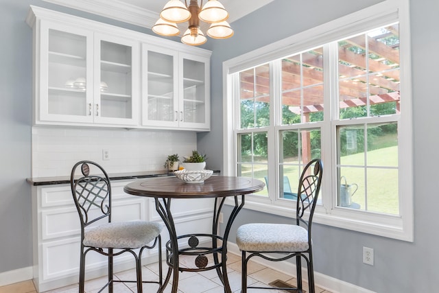 dining area featuring ornamental molding, light tile patterned flooring, and a notable chandelier