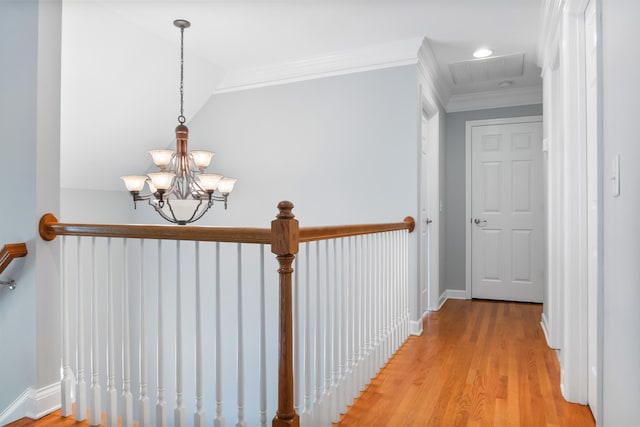 hallway featuring light hardwood / wood-style floors, ornamental molding, and a chandelier