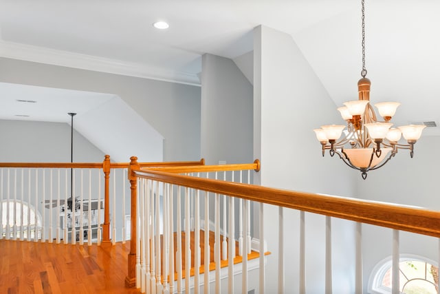 corridor with a notable chandelier, vaulted ceiling, hardwood / wood-style flooring, and ornamental molding