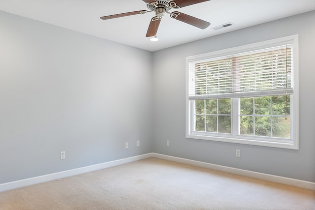 unfurnished room featuring ceiling fan, light colored carpet, and a wealth of natural light