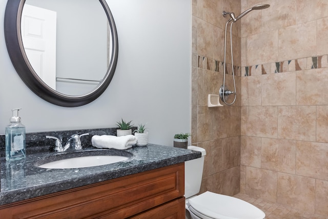 bathroom featuring vanity, toilet, and tiled shower