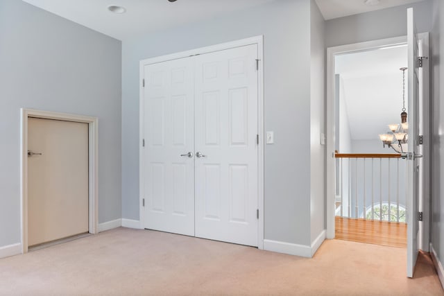 unfurnished bedroom with a notable chandelier, a closet, and light carpet