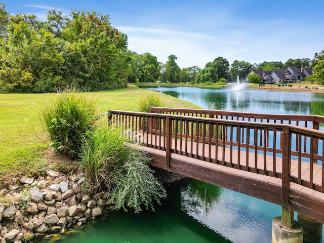 view of dock with a lawn and a water view