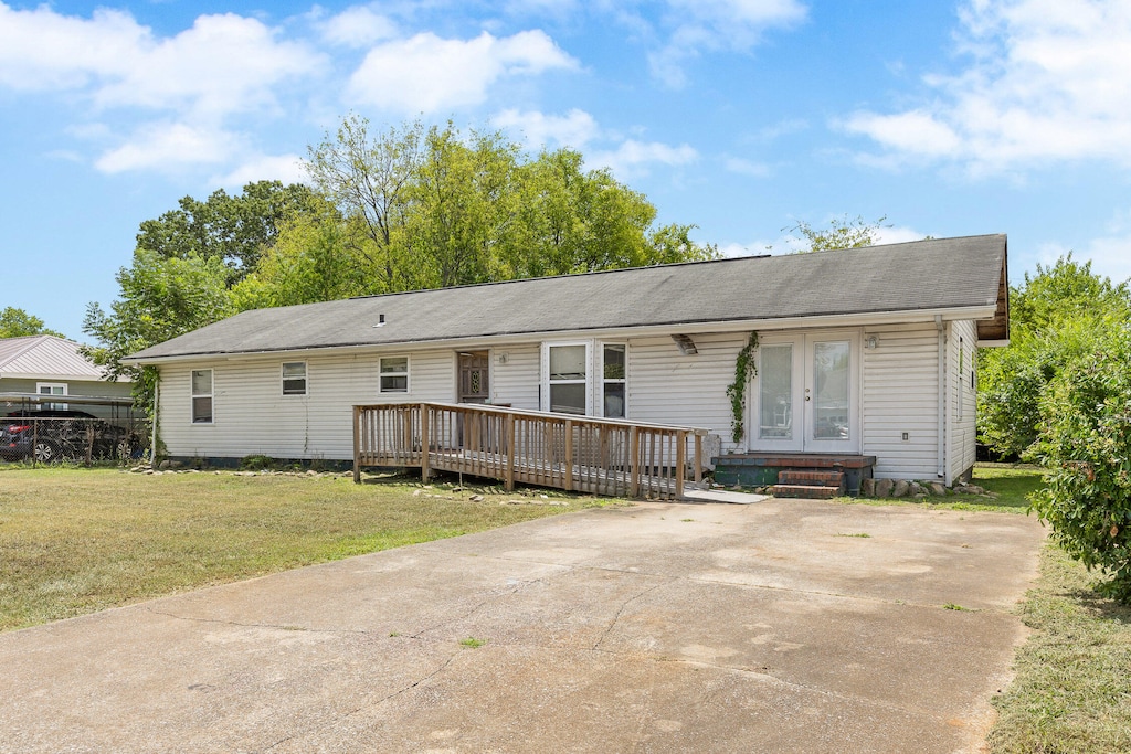 ranch-style house with a wooden deck and a front lawn