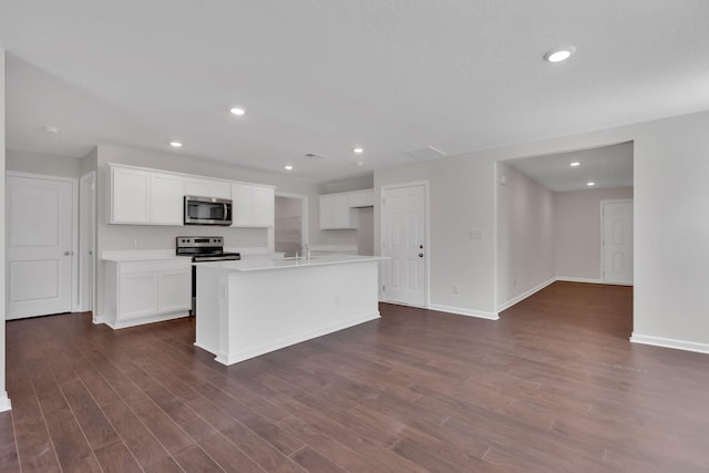 kitchen with white cabinets, appliances with stainless steel finishes, a center island with sink, and dark hardwood / wood-style flooring