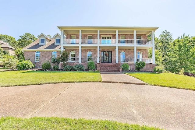 view of front of property with a balcony, a front yard, and a porch