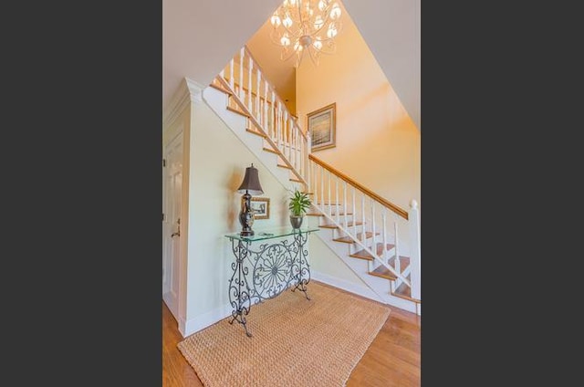 entryway featuring wood-type flooring, an inviting chandelier, and a high ceiling