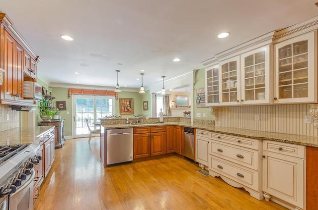 kitchen featuring decorative light fixtures, appliances with stainless steel finishes, light stone counters, and kitchen peninsula