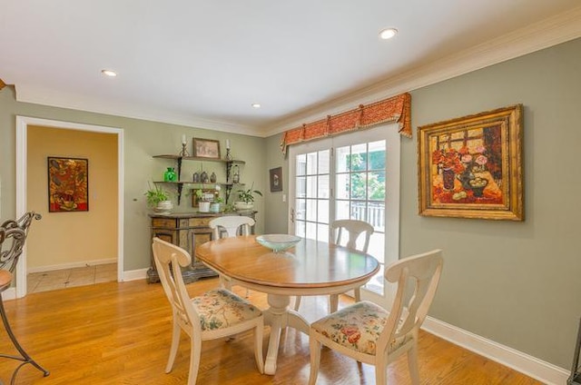 dining room with ornamental molding and light hardwood / wood-style floors