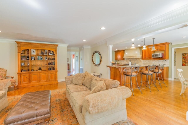 living room with crown molding, light hardwood / wood-style flooring, and decorative columns