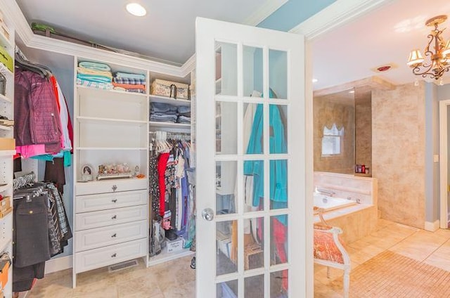 walk in closet with a chandelier and light tile patterned flooring