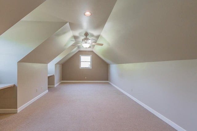 additional living space with ceiling fan, light colored carpet, and vaulted ceiling