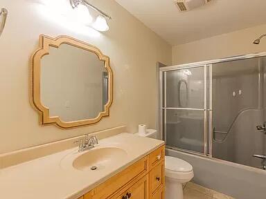 full bathroom with tile patterned floors, toilet, bath / shower combo with glass door, and vanity