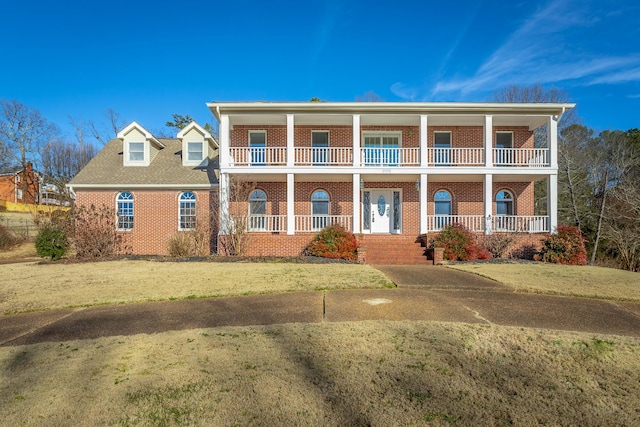 view of front facade with a balcony, covered porch, and a front lawn