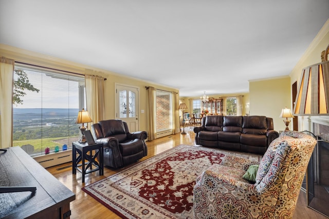 living room with ornamental molding, an inviting chandelier, a healthy amount of sunlight, and wood-type flooring