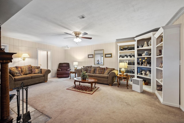 carpeted living room featuring ceiling fan, crown molding, and a textured ceiling