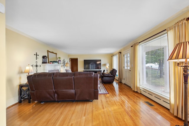 living room featuring light wood-type flooring, baseboard heating, and crown molding