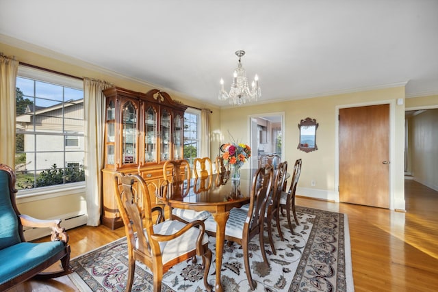 dining space featuring a healthy amount of sunlight, ornamental molding, hardwood / wood-style flooring, and a notable chandelier