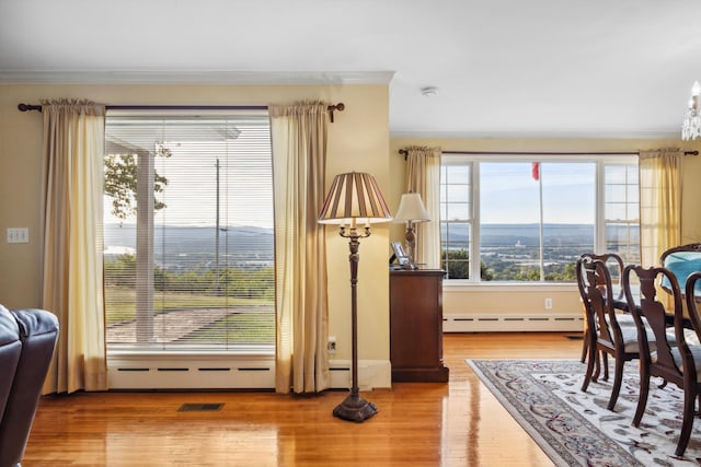 dining room featuring a baseboard heating unit, crown molding, and wood-type flooring