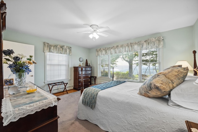 carpeted bedroom with a baseboard heating unit and ceiling fan