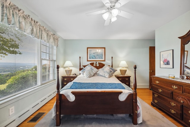 bedroom with baseboard heating, ceiling fan, and hardwood / wood-style flooring