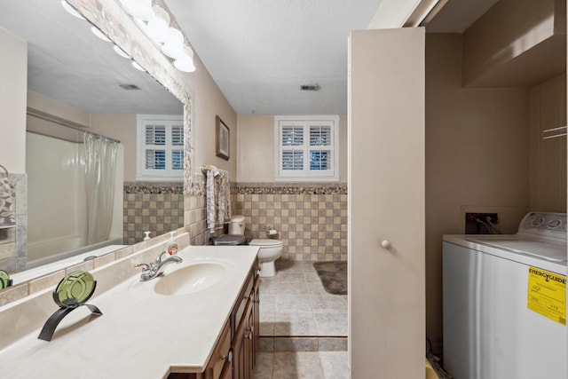 full bathroom featuring a textured ceiling, vanity, washer / clothes dryer, tile walls, and toilet