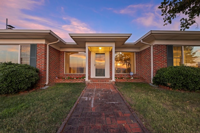 exterior entry at dusk featuring a lawn