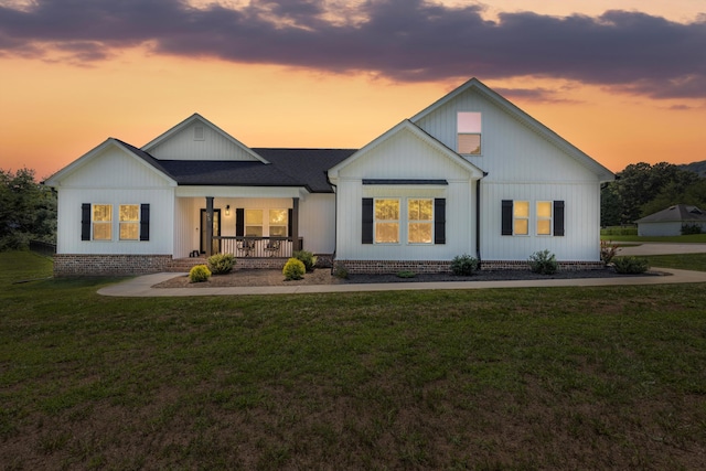 modern farmhouse style home with a porch and a lawn