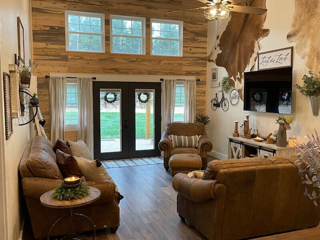 interior space featuring ceiling fan, french doors, a high ceiling, and wooden walls