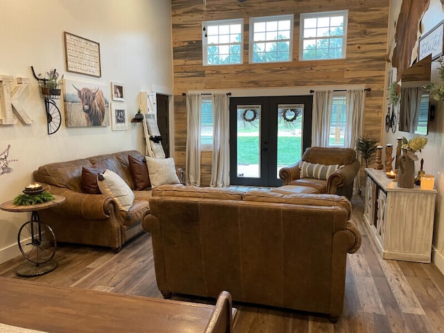 living room featuring dark hardwood / wood-style flooring, a towering ceiling, plenty of natural light, and wood walls