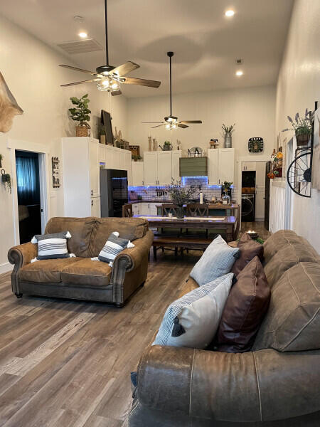 living room with washer / clothes dryer, ceiling fan, wood-type flooring, and a high ceiling