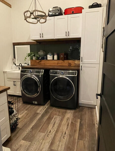 laundry area with cabinets, dark wood-type flooring, sink, washer and dryer, and a notable chandelier