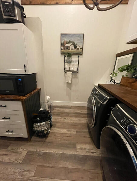 clothes washing area with cabinets, dark hardwood / wood-style flooring, and washer and clothes dryer