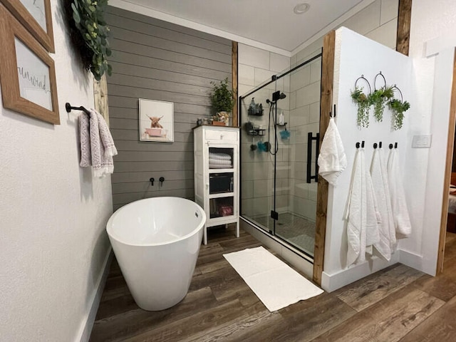 bathroom with hardwood / wood-style flooring, crown molding, and independent shower and bath