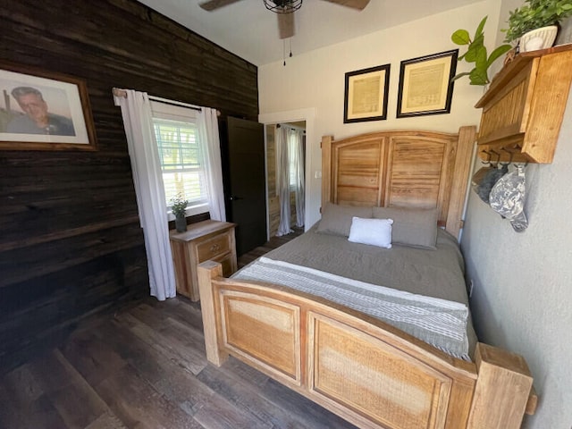 bedroom with ceiling fan, dark wood-type flooring, and wood walls