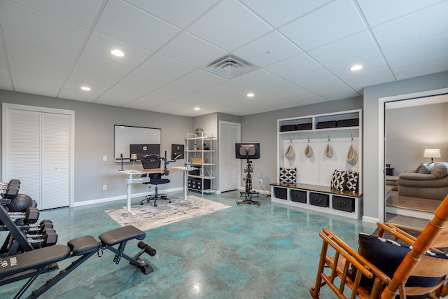 workout room featuring a paneled ceiling and concrete floors