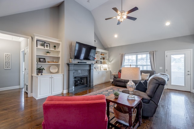 living room with dark wood-type flooring, ceiling fan, high vaulted ceiling, and a premium fireplace