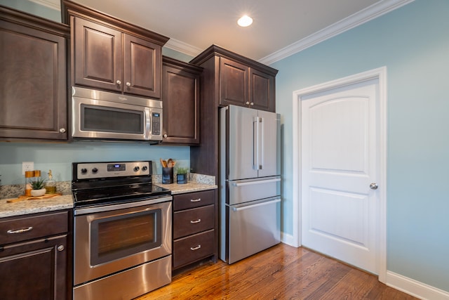 kitchen with crown molding, appliances with stainless steel finishes, wood-type flooring, and dark brown cabinetry