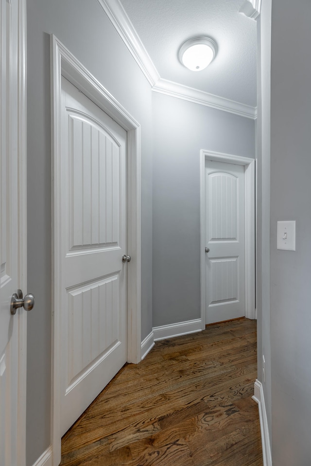 corridor featuring dark hardwood / wood-style floors, a textured ceiling, and ornamental molding