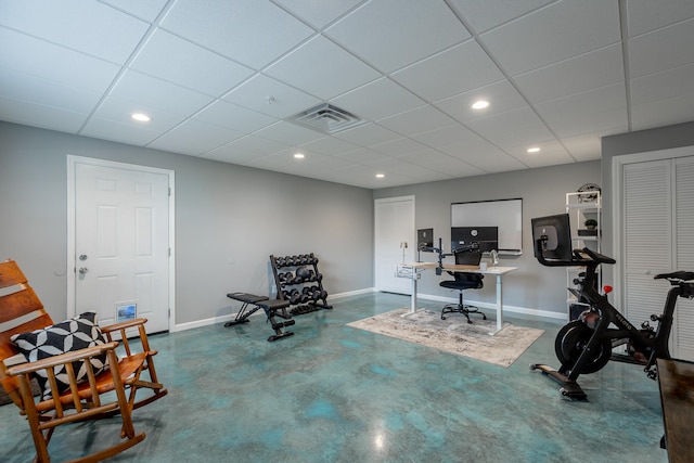 exercise room with concrete flooring and a drop ceiling