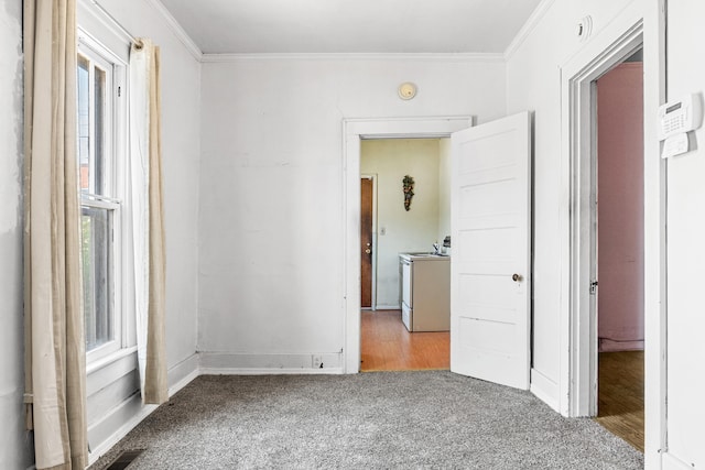 carpeted empty room featuring washer / clothes dryer, a wealth of natural light, and ornamental molding