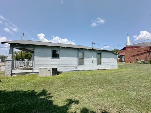 rear view of house with cooling unit and a yard