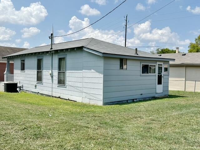 view of side of property featuring central AC unit and a lawn