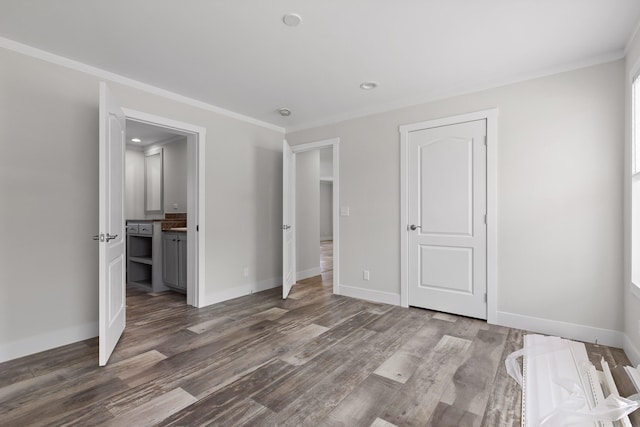 unfurnished bedroom with ornamental molding, connected bathroom, and dark wood-type flooring