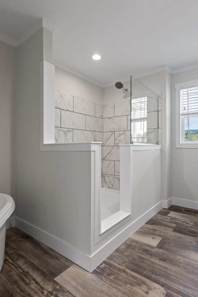 bathroom with crown molding, hardwood / wood-style flooring, and tiled shower