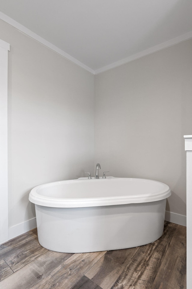 bathroom featuring wood-type flooring, ornamental molding, and a washtub