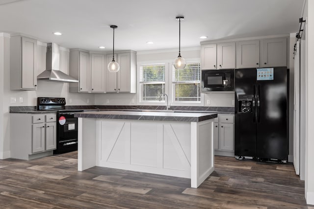 kitchen with wall chimney range hood, gray cabinetry, dark wood-type flooring, hanging light fixtures, and black appliances