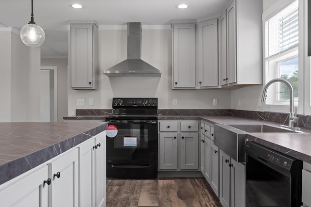 kitchen with wall chimney range hood, gray cabinetry, sink, dark hardwood / wood-style floors, and black appliances